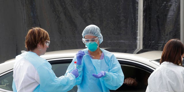 Health care personnel test a person in the passenger seat of a car for coronavirus at a Kaiser Permanente medical center parking lot in San Francisco, Thursday, March 12, 2020. (AP Photo/Jeff Chiu)