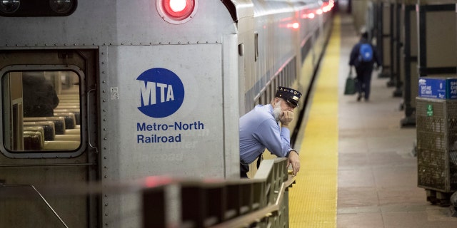 A conductor waits for customers to embark a train at Grand Central Terminal, Tuesday, March 17, 2020, in New York.