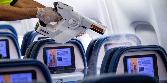 Members of Delta's line maintenance crew disinfect the surfaces of the cabin including tray tables, seat backs and in-flight entertainment screens in a Boeing 757. (Chris Rank for Rank Studios)