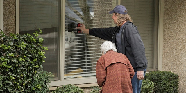 Dorothy Campbell and her son, Charlie Campbell, talk through a window with her husband, Gene Campbell, at the Life Care Center of Kirkland, the long-term care facility linked to several confirmed coronavirus cases in the state, in Kirkland, Washington, U.S. March 5, 2020. 