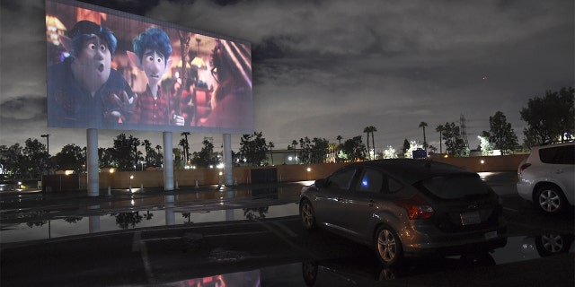 Viewers in a parked car watch the animated film "Onward" at the Paramount Drive-In Theatres, Thursday, March 19, 2020, in Paramount, Calif. The drive-in theater, long a dwindling nostalgia act in a multiplex world, is experiencing a momentary return to prominence. With nearly all of the nation’s movie theaters shuttered due to the pandemic, some drive-in owners think they’re in a unique position to give moviegoers a chance to do something out of the house but stay within prudent distance from one another. (AP Photo/Chris Pizzello)