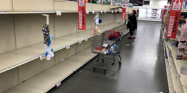 A woman shops among empty shelves at a Hy-Vee food store Friday, March 13, 2020, in Overland Park, Kan. (AP Photo/Charlie Riedel)