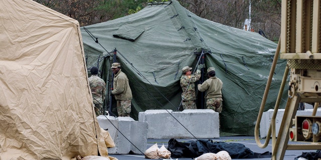 The National Guard sets up tents to be used for coronavirus testing, Saturday, March 21, 2020, in a parking lot for FedEx Field in Landover, Md., outside of Washington. (AP Photo/Jacquelyn Martin)