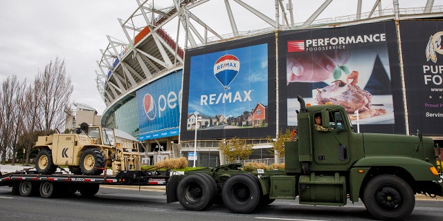 Equipment is driven by FedEx Field as the National Guard sets up tents to be used for coronavirus testing, Saturday, March 21, 2020, in a parking lot at the NFL football stadium in Landover, Md., outside of Washington. (AP Photo/Jacquelyn Martin)