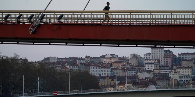 A man runs alone on an empty bridge in Lyon, central France, Saturday, March 21, 2020. French citizens are only allowed to leave their homes for necessary activities such as shopping for food, going to work or taking a quick walk due to the rapid spreading of the new coronavirus in the country.