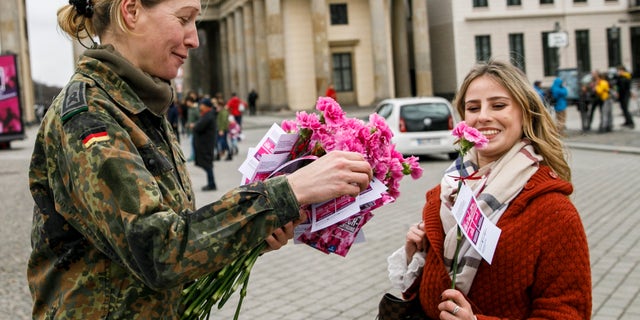 A soldier of the Bundeswehr hands out a carnation to a passerby in front of the Brandenburg Gate on International Women's Day on March 8, 2019 in Berlin, Germany.