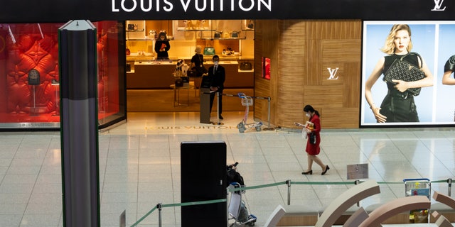 A woman wearing a protective mask walks past a Louis Vuitton store in the duty free shopping area at Incheon International Airport in South Korea on March 3.