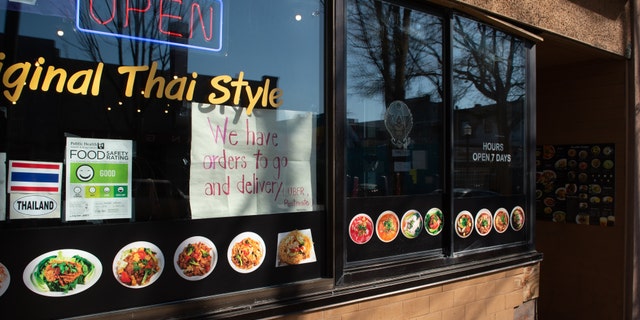 A sign indicating take out and delivery services are available is displayed in a window of a restaurant in the University District of Seattle, Washington on March 18.
