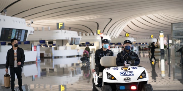 Two police officers wearing face masks drive an electric vehicle in Beijing Daxing International Airport, China, on March 3.