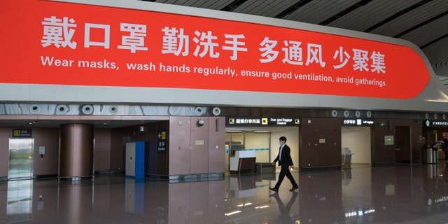 A man walks past a LED wall displaying a message with English translation about the prevention of the spread of coronavirus in Beijing Daxing International Airport, China on March 3.