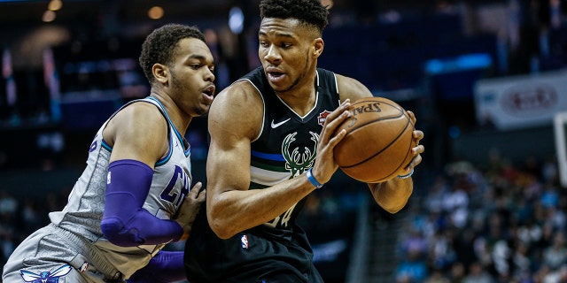 Milwaukee Bucks forward Giannis Antetokounmpo, right, looks to drive against Charlotte Hornets forward P.J. Washington in the first half of an NBA basketball game in Charlotte, N.C., Sunday, March 1, 2020. (AP Photo/Nell Redmond)