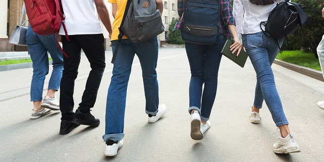 Unrecognizable teenage students in high school campus walking at break.