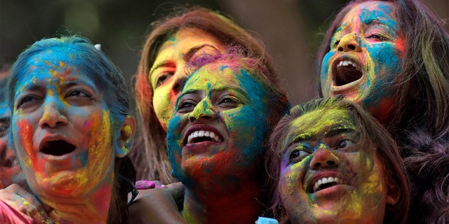 Women with their faces smeared with colored powder cheer during celebrations marking the Holi festival in Mumbai, India, Tuesday. Holi, the festival of colors heralds the arrival of spring (AP Photo/Rajanish Kakade)