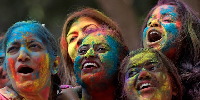 Women with their faces smeared with colored powder cheer during celebrations marking the Holi festival in Mumbai, India, Tuesday. Holi, the festival of colors heralds the arrival of spring (AP Photo/Rajanish Kakade)