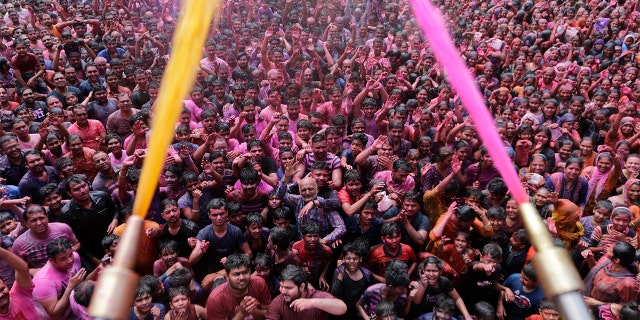 Indian Hindu devotees cheer as colored powder and water is sprayed on them by a Hindu priest during celebrations marking Holi at the Swaminarayan temple in Ahmedabad, India, Tuesday. Holi, the Hindu festival of colors, also marks the advent of spring. (AP Photo/Ajit Solanki)