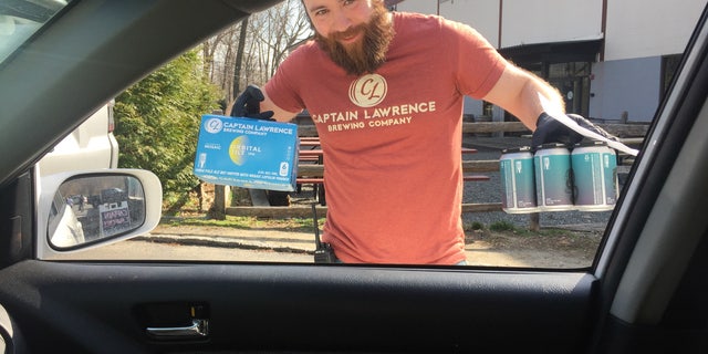 Rob, an employee of Captain Lawrence Brewing Co. in Elmsford, New York, makes a curbside no-contact drink delivery while wearing rubber gloves as part of the brewery's coronavirus precautions, and efforts to stay afloat during the statewide shutdown.Capt. Lawrence is using brewing equipment to make hundreds of gallons of chicken soup for a local food industry worker charity. 