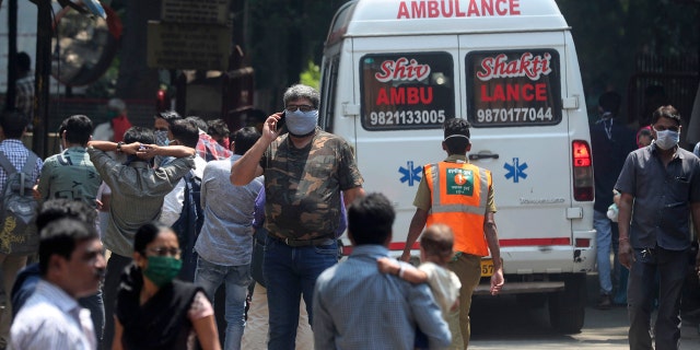 People wearing masks walk outside a special ward for possible COVID-19 patients at a hospital in Mumbai, India, Tuesday, March 17, 2020.