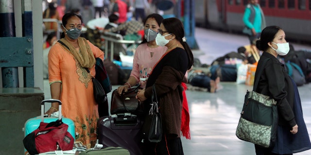Indian passengers wearing masks as a precaution against the new coronavirus wait at railway station in Jammu, India, Tuesday, March 17, 2020.
