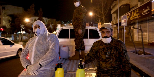 In this Wednesday, March 4, 2020, photo, Revolutionary Guard members take part in disinfecting the city to help prevent the spread of the new coronavirus in Tehran, Iran. Wearing gas masks and waterproof fatigues, members of Iran's Revolutionary Guard now spray down streets and hospitals with disinfectants as the Islamic Republic faces one of the world's worst outbreaks of the new coronavirus. (AP Photo/Ebrahim Noroozi)