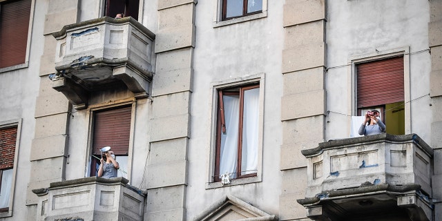 People leaning out of their home's balconies in Milan to play and sing during a flash mob launched throughout Italy to bring people together and try to cope with the emergency of coronavirus. (Claudio Furlan/LaPresse via AP) People leaning out of their home's balconies in Milan to play and sing during a flash mob launched throughout Italy to bring people together and try to cope with the emergency of coronavirus. (Claudio Furlan/LaPresse via AP)