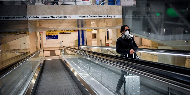 A woman wearing a mask on an escalator inside Milan's central train station Sunday. (Claudio Furlan/LaPresse via AP)