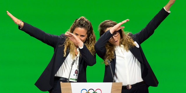In this Monday, June 24, 2019 filer, Italian snowboarder Michela Moioli, left, and Italian skier Sofia Goggia, right, dab after speaking during the presentation of the Milan-Cortina candidate cities the first day of the 134th Session of the International Olympic Committee (IOC), in Lausanne, Switzerland.