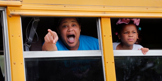 A congregant in a church bus yells out to news media as they leave services at the Life Tabernacle Church in Central, La., Sunday, March 29, 2020. Pastor Tony Spell has defied a shelter-in-place order by Louisiana Gov. John Bel Edwards, due to the new coronavirus pandemic, and continues to hold church services with hundreds of congregants. (AP Photo/Gerald Herbert)