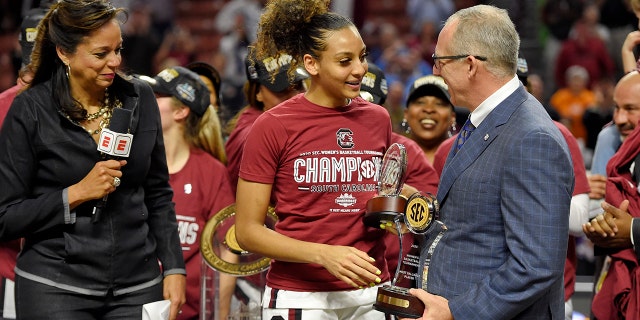 South Carolina's Mikiah Herbert-Harrigan, center, is presented with the MVP trophy by SEC Commissioner Greg Sankey, right, as ESPN's Carolyn Peck watches after defeating Mississippi State 76-62 in a championship match at the Southeastern Conference women's NCAA college basketball tournament in Greenville, S.C., Sunday, March 8, 2020. (AP Photo/Richard Shiro)