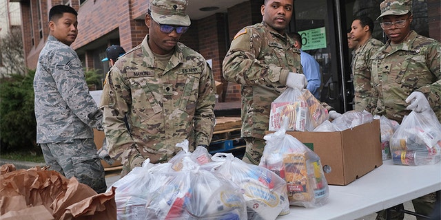 Members of the New York National Guard help to organize and distribute food to families on free or reduced school lunch programs in New Rochelle, N.Y., Thursday, March 12, 2020. (Associated Press)