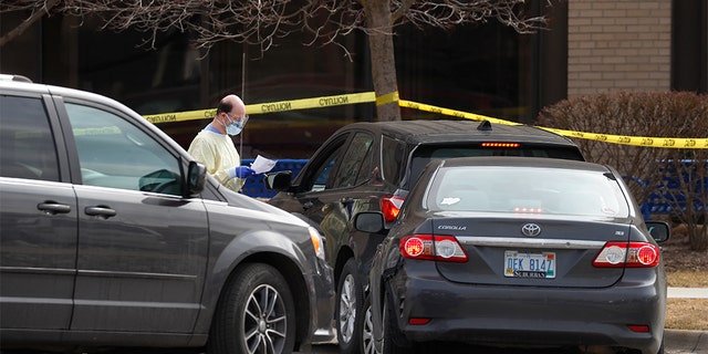 A healthcare worker screens people for COVID-19, the disease that is caused by the new coronavirus, at a drive-through station set up in the parking lot of the Beaumont Hospital in Royal Oak, Mich. on March 16. Skylar Herbert, the first child to die from the coronavirus in the state on Sunday had been admitted to the hospital. (AP Photo/Paul Sancya)