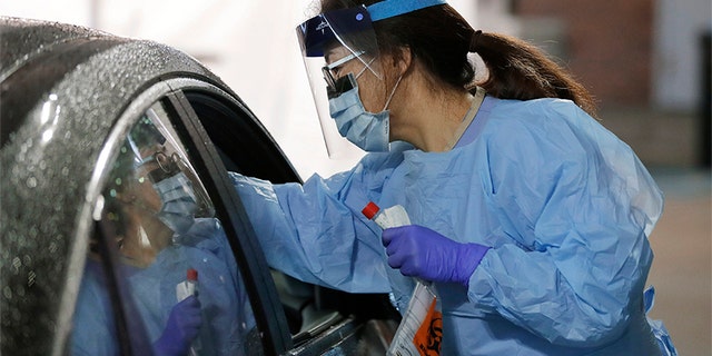 A nurse at a drive-up coronavirus testing station set up by the University of Washington Medical Center uses a swab to take a sample from the nose of a person in a car Friday, March 13, 2020, in Seattle. (Associated Press)