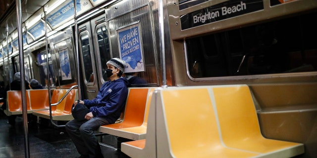 A commuter wears a face mask while riding a nearly empty subway car into Brooklyn, Thursday, March 12, 2020, in New York. New York City Mayor Bill de Blasio said Thursday he will announce new restrictions on gatherings to halt the spread of the new coronavirus in the coming days, but he hopes to avoid closing all public events such as Broadway shows. For most people, the new coronavirus causes only mild or moderate symptoms. For some it can cause more severe illness.