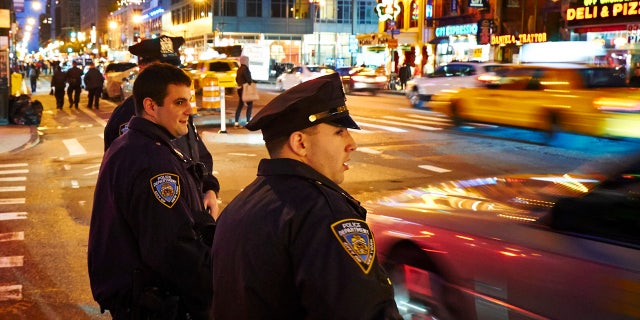 New York, USA - May 21, 2013: Three NYPD Police officers patrols streets of Manhattan in New York City at night.