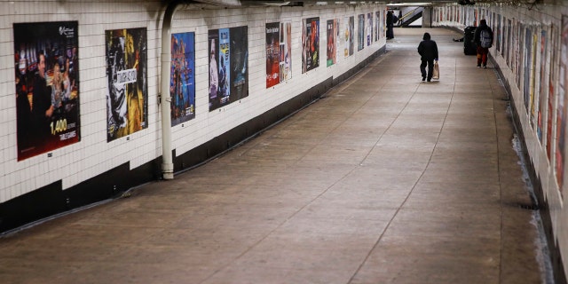 A subway customer walks through an empty underground passage in the Brooklyn borough of New York, Monday, March 16, 2020.