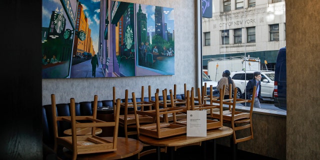 Chairs are stacked in a Starbucks coffee shop that remained open for customers purchasing for take-away, Monday, March 16, 2020, in New York.