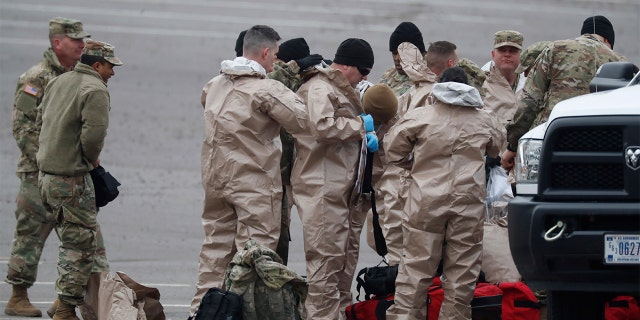 Colorado National Guard medical personnel suit up to perform coronavirus tests on motorists at a drive-through testing site outside the Denver Coliseum Saturday, March 14, 2020, in Denver. Officials planned to administer 150 tests but the line of vehicles wrapped around three city blocks. For most people, the new coronavirus causes only mild or moderate symptoms. For some it can cause more severe illness.(AP Photo/David Zalubowski)