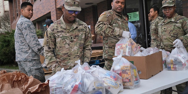 Members of the New York National Guard help to organize and distribute food to families on free or reduced school lunch programs in New Rochelle, N.Y., Thursday, March 12, 2020. State officials have set up a “containment area” in the New York City suburb. (AP Photo/Seth Wenig)