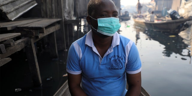 A man wearing a face mask sits in a traditional canoe at the Makoko community in Lagos, Nigeria March 9, 2020. (REUTERS/Temilade Adelaja)