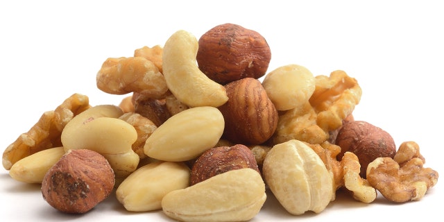 A pile of shelled hazelnuts, walnuts,cashew nuts and almonds, isolated on a white background.
