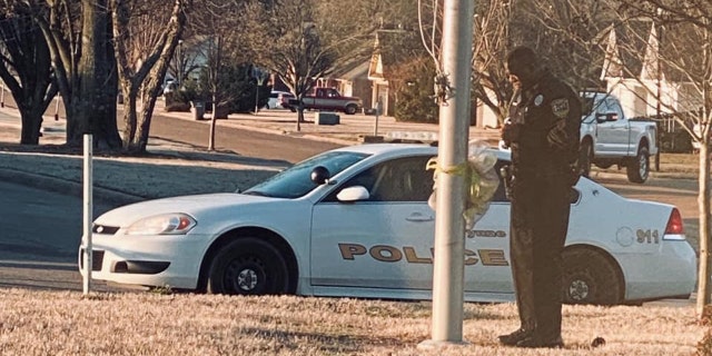 Officer DeAndra Warren stands at the flag pole, praying for students. The photo shared by his 21-year-old daughter, De'Andria, went viral online.