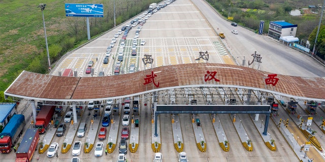 In this March 24, 2020, photo released by Xinhua News Agency, an aerial photo shows vehicles waiting to cross into Wuhan at a highway toll station in Wuhan, in central China's Hubei Province. Hubei has ended a lockdown for most of the province, allowing people who have passed health checks to leave for the first time in two months. The provincial capital of Wuhan, where the virus hit hardest, remains locked down until April 8. (Cai Yang/Xinhua via AP)