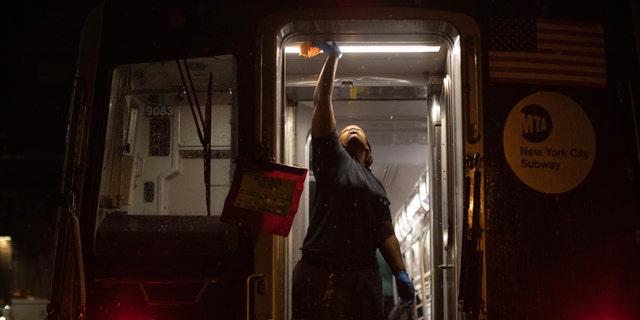 In this March 3, 2020, file photo, Metropolitan Transportation Authority worker sanitizes surfaces at the Coney Island Yard, in the Brooklyn borough of New York. 