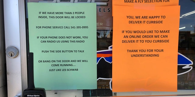 In this photo taken March 20, 2020, a sign outside a fly fishing shop in tiny Maupin, Oregon, advises customers of new policies to limit the spread of the new coronavirus in rural areas. (AP Photo/Gillian Flaccus)