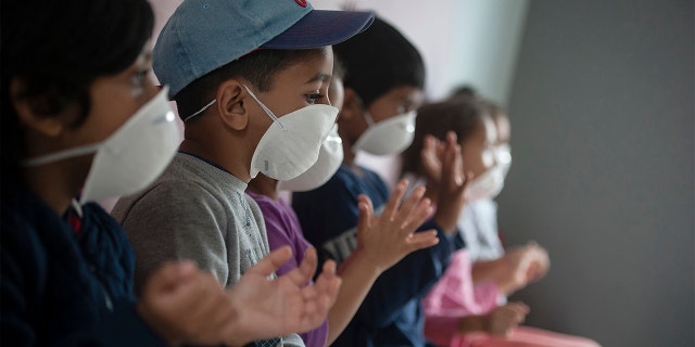Learners wear masks as they sanitise their hans at a pre-school in Lenasia, Johannesburg, Tuesday, March 17, 2020, on the day schools closed in a bid to control the spread of coronavirus. (AP Photo/Shiraaz Mohamed)