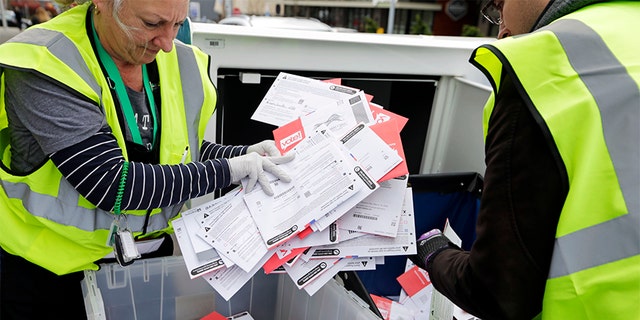 King County election workers collect ballots from a drop box in the Washington state primary, Tuesday, March 10, 2020 in Seattle. Washington is a vote-by-mail state. (AP Photo/John Froschauer)