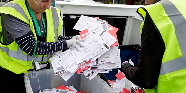 King County Election workers collect ballots from a drop box in the Washington State primary on Tuesday, March 10, 2020, in Seattle. (AP Photo/John Froschauer)