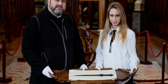 Father Serafino Jamourlian and Vittoria Dall'Armellina with the sword. (Photo credit: Andrea Avezzù/Ca' Foscari University of Venice)