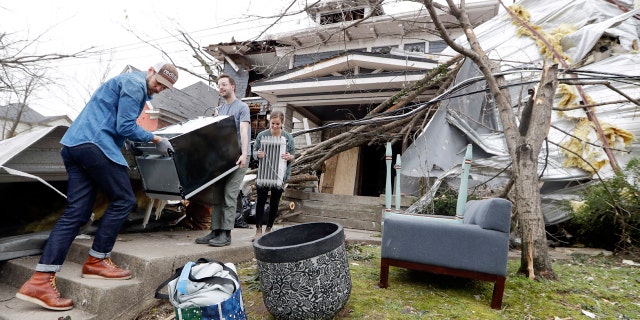 Benji Peck, left, and Austin Grove remove a refrigerator from a damaged home Wednesday, March 4, 2020, in Nashville, Tenn. Residents and businesses face a huge cleanup effort after tornadoes hit the state Tuesday.