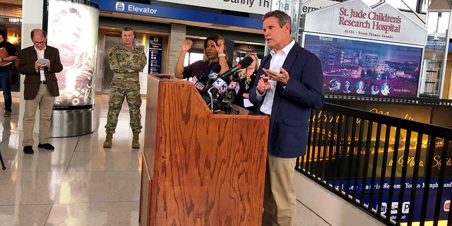 Tennessee Gov. Bill Lee (right, at podium) speaks to reporters at Memphis International Airport about the state's response to the new coronavirus on Friday, March 27, 2020, in Memphis, Tenn. (AP Photo/Adrian Sainz).