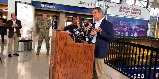 Tennessee Gov. Bill Lee (right, at podium) speaks to reporters at Memphis International Airport about the state's response to the new coronavirus on Friday, March 27, 2020, in Memphis, Tenn. (AP Photo/Adrian Sainz).